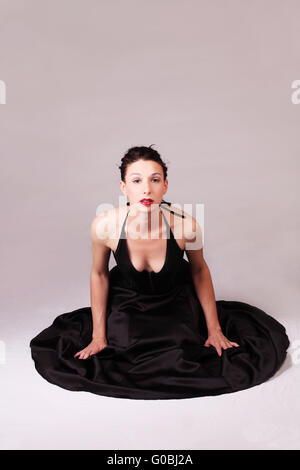Young woman in black skirt and corset on floor Stock Photo