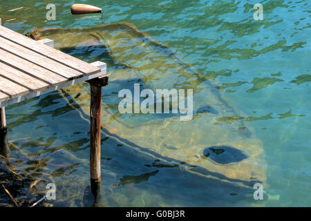Old rowing boat sunken under water at a wooden jet Stock Photo