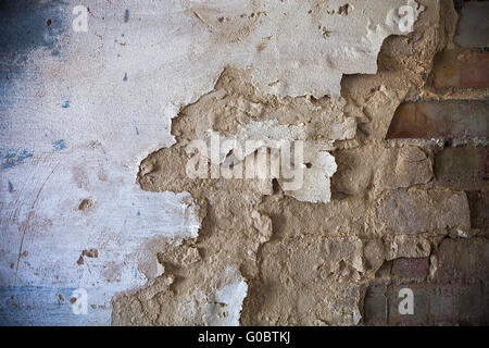 Damaged whitewashed plaster on the brick wall Stock Photo