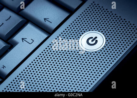 Closeup of silver blue computer laptop selective focus on standby on button ideal for technology business start power energy sym Stock Photo