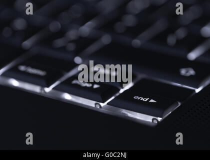 Closeup of backlit computer laptop keyboard selective focus on end key ideal for technology night hacker standout Stock Photo