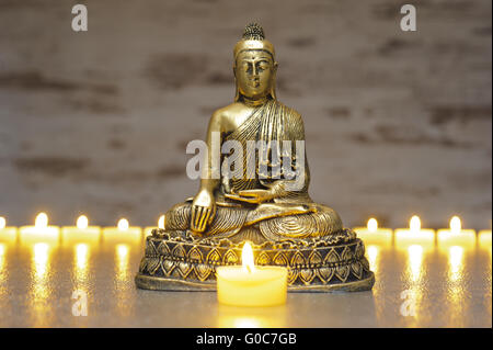 Buddha sitting in meditation with line of candle Stock Photo