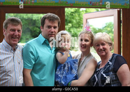 family standing together wearing party hat celebrating a child's birthday party, family fun concept, family portrait, grandparents, togetherness Stock Photo