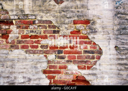 Very old street fence wall built from red bricks and painted Stock Photo