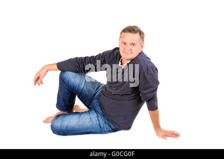 Casually dressed middle aged man sitting on a floor barefoot Stock Photo