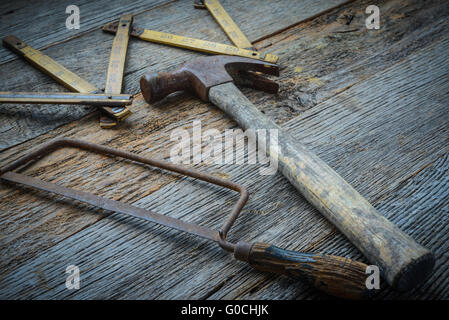 Hammer, Saw and Measuring Tape on Rustic Wood Background Stock Photo