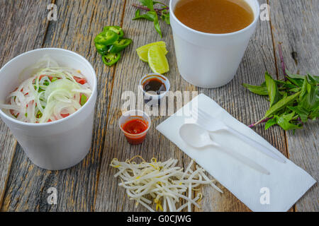 Pho Fast Food To Go on Wood Background with Peppers and Basil Stock Photo