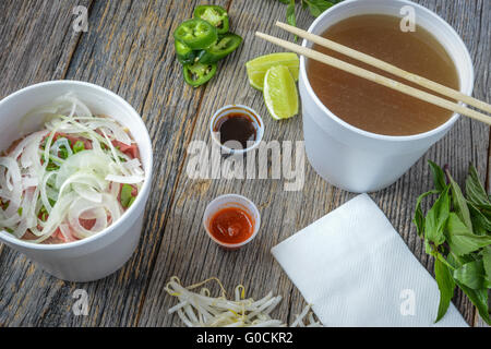 Pho Fast Food To Go on Wood Background with Peppers and Basil Stock Photo