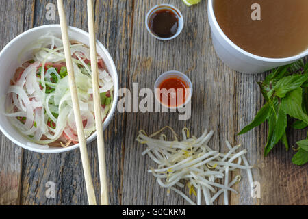 Pho Fast Food To Go on Wood Background with Peppers and Basil Stock Photo