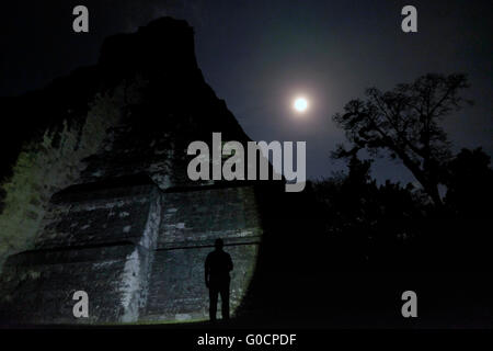 Full moon rises behind the ancient Mayan stepped pyramid temple number1 also known as the Big Jaguar built in the year 700 AD at the Gran Plaza at the archaeological site of Tikal an ancient urban center of the pre-Columbian Maya civilization located in the archaeological region of the Peten Basin in northern Guatemala Stock Photo