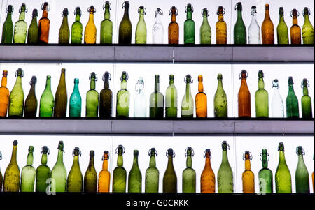 Many different, empty, beer bottles, most with ceramic cap, standing in a lighted shelf, Stock Photo