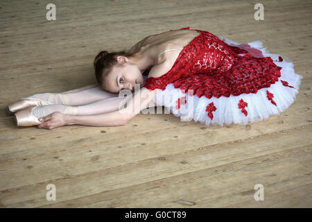 Charming young dancer doing stretching leaned over, looking at t Stock Photo