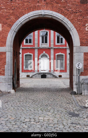 Cobblestone road and gate to the main building of the Stavelot Abbey seen through a archway. Stock Photo