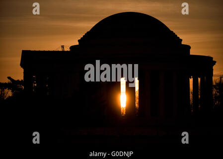 Jefferson Memorial Silhouette Sunrise / WASHINGTON D.C., United States — The Jefferson Memorial is silhouetted against a deep orange sunrise, the rising sun burning through the gap between its Ionic columns at the Tidal Basin. Architect John Russell Pope modeled the rotunda directly on the Roman Pantheon, a deliberate choice to honor Jefferson's own passion for classical architecture and his role in shaping the neoclassical vocabulary of the early republic. Stock Photo