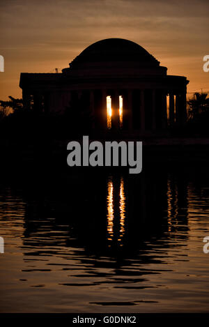 WASHINGTON, D.C., United States — The Jefferson Memorial is dramatically silhouetted against the rising sun over the Tidal Basin in Washington, D.C. This iconic view captures the neoclassical monument's distinctive dome and colonnade in stark contrast with the golden light of dawn. Stock Photo