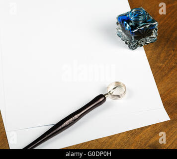Ink pot and quill with sheets of paper on a table Stock Photo