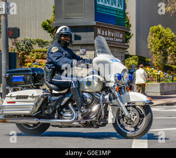 A smiling African American motorcycle policeman traveling by the Nashville Convention Center in Nashville, TN, Music City, USA Stock Photo