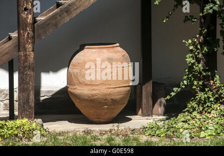 Big old clay cruse under old wooden house ladder Stock Photo