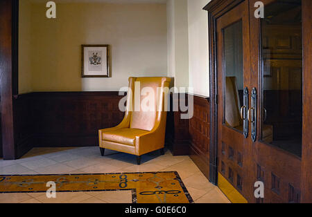 Lone stylized tall back chair in corner of beautifully tiled floor room with dark wood waistcoating looks mysteriously arty Stock Photo