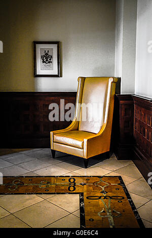 Lone stylized tall back chair in corner of beautifully tiled floor room with dark wood waistcoating looks mysteriously arty Stock Photo