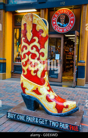 A huge yellow & red plaster promo cowboy boot, artistically rendered in resin fronts The Nashville Cowboy boot store,  downtown Nashville TN Stock Photo