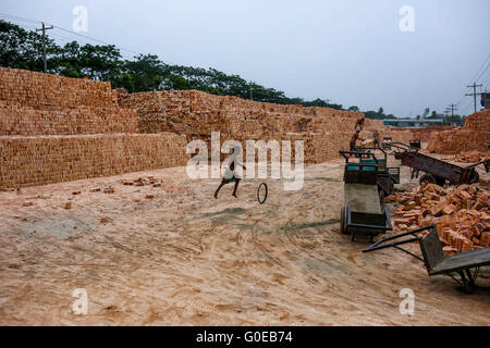 Dhaka, Bangladesh. 1st May, 2016. A girl is playing with a bicycle tyre in a brickfield. Brickfield is a place where hundreds of children live with their working parents and growing up here in dusty environment and without any kind of formal education which is leading them towards uncertain future. © Mohammad Ponir Hossain/ZUMA Wire/Alamy Live News Stock Photo