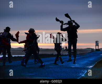 'Rag Bag Morris' marking May Day on the causeway to the Holy Island of Lindisfarne, Northumberland. Every year they dance at sunrise on May Day at a different location in north Northumberland or the Scottish Borders. Stock Photo