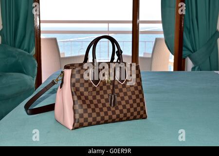 A Louis Vuitton handbag on a bed with a blue sheet Stock Photo