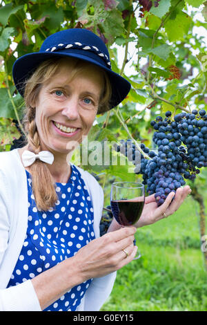 Woman holding glass of wine near bunch of blue gra Stock Photo