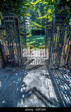 Classical design black wrought iron gate in a beautiful green garden ...