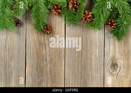 Christmas border with branches and pinecones on rustic wooden boards Stock Photo