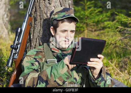 Young recruit with tablet PC and optical rifle in Stock Photo