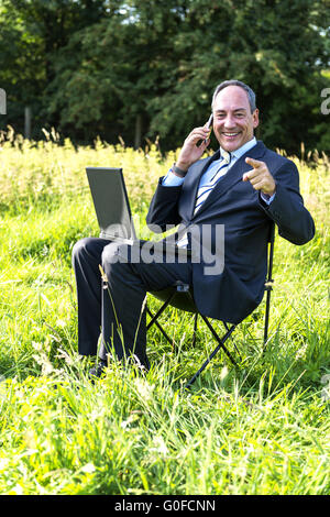 Businessman on meadow - green IT Stock Photo