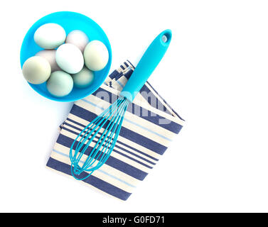Eggs in a blue bowl with a whisk on a white background shot from above Stock Photo