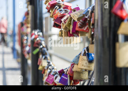Wedding locks hanging on the railing of the bridge over the old stream. Stock Photo