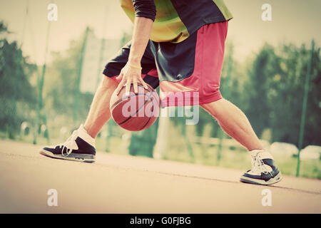 Young man on basketball court dribbling with ball. Streetball Stock Photo