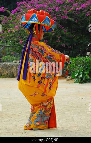 Okinawa, Japan - May 13, 2007: A female adult wearing traditional Okinawan clothing entertains tourists with traditional Okinawan dancing. Stock Photo