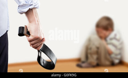 Angry man raised hand holding belt over child boy Stock Photo