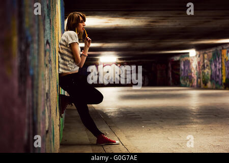 Stylish young girl standing in grunge graffiti tunnel Stock Photo