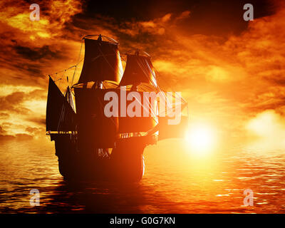 Ancient pirate ship sailing on the ocean at sunset. In full sail. Stock Photo