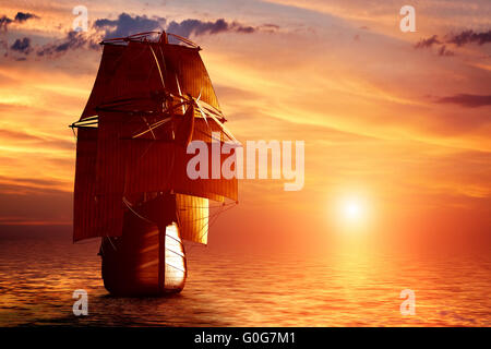 Ancient pirate ship sailing on the ocean at sunset. In full sail. Stock Photo