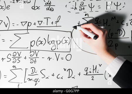 Man writing complex math formulas on whiteboard. Mathematics and science Stock Photo