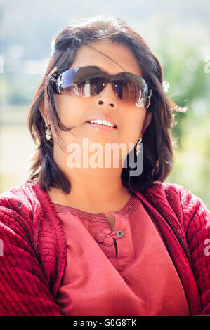 Portrait of a mature, Asian, Non-Caucasian, Bengali beautiful smiling lady with copy space wearing red dress and backlit Stock Photo