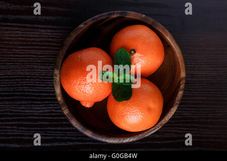 Mandarins in wooden plate on dark background close-up macro Stock Photo