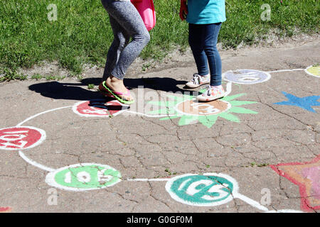 girls run on the childish drawings on the asphalt of street Stock Photo