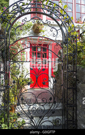 Red door of a residential building behind a wrought iron gate. Stock Photo