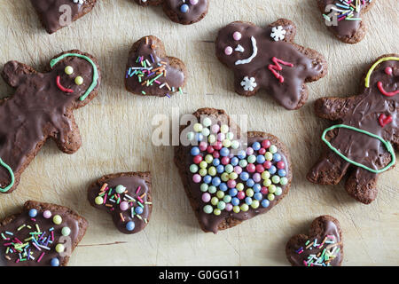 Handmade decorated gingerbread heart and people figures lying on wooden table. Christmas Stock Photo