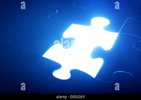 Jigsaw puzzle piece missing. Light glow from empty space. Search for the solution Stock Photo