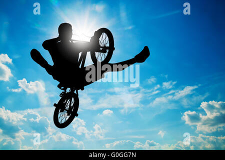 Man jumping on bmx bike performing a trick against sunny sky. Extreme sport Stock Photo