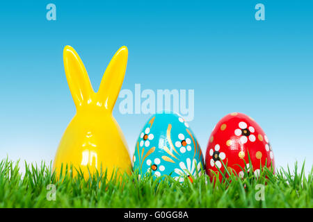 Hand painted Easter eggs and bunny rabbit toy on grass. Floral Stock Photo